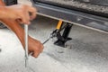 Hands using hydraulic jack - car maintenance concept. Car tire changed for maintenance in garage