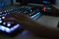 Hands using an illuminated keyboard and mouse. Blurred image.