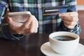 Hands using smart phone and holding credit card for shopping online in coffee cafe Royalty Free Stock Photo