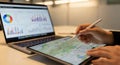 Hands using stylus on tablet with charts on laptop screen Royalty Free Stock Photo