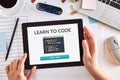 Hands using tablet with learn to code concept on screen