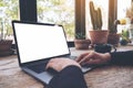 Hands using and typing on laptop with blank white desktop screen on vintage wooden table in cafe Royalty Free Stock Photo