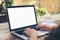 Hands using and typing on laptop with blank white screen on vintage wooden table in outdoor cafe Royalty Free Stock Photo