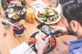 Hands view of influencer man eating brunch while making video of dish with mobile phone in trendy bar restaurant - Healthy