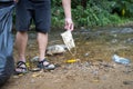 Hands of volunteer is picking up trash,rubbish of face mask with garbage bag on the streams of waterfalls,dirty nature,problem of
