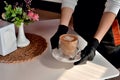 Hands of a waitress in medical gloves with a coffee mug, in a cafe, virus, medical safety pandemic