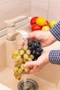 Hands washing grapes in the sink on kitchen. Washing fruits and vegetables concept Royalty Free Stock Photo