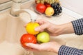 Hands washing tomato, apple and lemon in the sink on kitchen. Washing fruits and vegetables concept Royalty Free Stock Photo