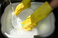 Hands washing up dishes in yellow gloves