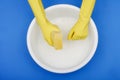 Hands wearing rubber gloves, plastic basin, sponge