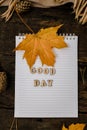 Hands and White blank notebook with wooden letters phrase Good day on a dark background with a scarf, plaid and cup, autumn yellow Royalty Free Stock Photo