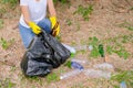 Hands of white shirt woman collect the garbage out from grasses and soil to black bag in the garden with concept save the Royalty Free Stock Photo