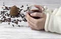 Hands in a white sweater, a cup of tea, a pine cone and pine nuts, a white wooden background Royalty Free Stock Photo