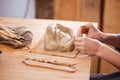 Hands of woman ceramist finishing sculpture with clay in workshop