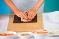 Hands of woman chef filling japanese sushi rolls with rice on a nori seaweed sheet. Royalty Free Stock Photo