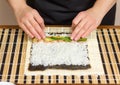 Hands of woman chef rolling up a japanese sushi