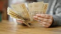 Hands of woman counting hundred denmark krone banknotes at room