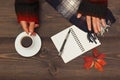 Hands of woman with a cup of coffee and scarf at wooden table with notebook and pen and autumn leaves Royalty Free Stock Photo