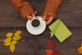 Hands of woman with a cup of espresso at a wooden table with notebook and pen and autumn leaves Royalty Free Stock Photo