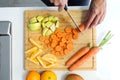 Hands of a woman cutting some vegetables and fruits in wooden table in the kitchen. Royalty Free Stock Photo