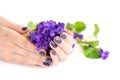 Hands of a woman with dark manicure on nails and bouquet of violets on a white background Royalty Free Stock Photo