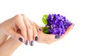 Hands of a woman with dark manicure on nails and bouquet of violets on a white background Royalty Free Stock Photo