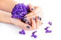 Hands of a woman with dark manicure on nails and bouquet of violets on a white background Royalty Free Stock Photo