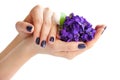 Hands of a woman with dark manicure on nails and bouquet of violets on a white background Royalty Free Stock Photo