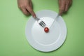 hands of woman eating one cherry tomato in her white plate on green background - Dieting concept Royalty Free Stock Photo