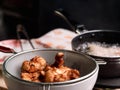 Hands of a woman in gloves are frying the marinated chicken in hot oil in a pan on the kitchen stove and tong the cooked chicken Royalty Free Stock Photo