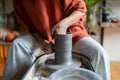 Hands of woman handmade ceramic make shape vessel from natural clay placed on rotating potter wheel