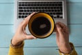 Hands of a woman holding a cup with coffee on a laptop Royalty Free Stock Photo