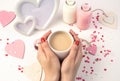 Hands of a woman holding a Cup of milk coffee on a background of hearts, a white frame and bottles of milk on a white Royalty Free Stock Photo