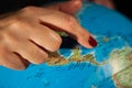 Hands of a woman holding a globe of the planet earth with marked places to travel on vacation