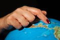 Hands of a woman holding a globe of the planet earth with marked places to travel on vacation