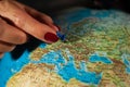 Hands of a woman holding a globe of the planet earth with marked places to travel on vacation