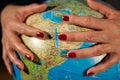 Hands of a woman holding a globe of the planet earth with marked places to travel on vacation