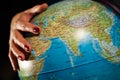 Hands of a woman holding a globe of the planet earth with marked places to travel on vacation