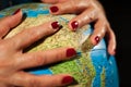 Hands of a woman holding a globe of the planet earth with marked places to travel on vacation