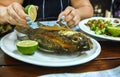 Hands of a woman holding a lemon and pouring fried fish on a plate Slave restaurant.