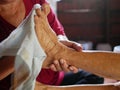 Hands of a woman holding an older person`s feet, while gently wiping / cleaning it with a wet washcloth - giving an elderly a bed