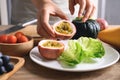 Hands of woman holding sliced passion fruit and preparing vegetables for vegan food cooking Royalty Free Stock Photo