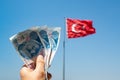 Hands of woman holding 300 Turkish Lira notes in front of flag