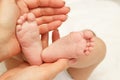 Hands of woman holds baby foot, blurred background Royalty Free Stock Photo