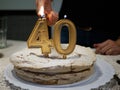 Hands of a woman lighting Golden candles four and zero of a birthday cake celebrating 40th Royalty Free Stock Photo
