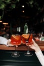 hands of woman and man are clinking, cheers with glasses of Spritz cocktail. Couple celebrating wedding, anniversary