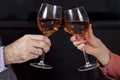 Hands of a woman and a man with wine glasses in hands are toasting. Wine glasses with a dark background Royalty Free Stock Photo