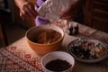 Hands of a woman mixing ground walnut with cocoa, raisins and Turkish delicacies in the kitchen. preparing a traditional cake reci