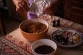 Hands of a woman mixing ground walnut with cocoa, raisins and Turkish delicacies in the kitchen. preparing a traditional cake reci