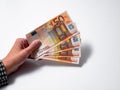 A woman`s hand offering fifty euro bills on white background